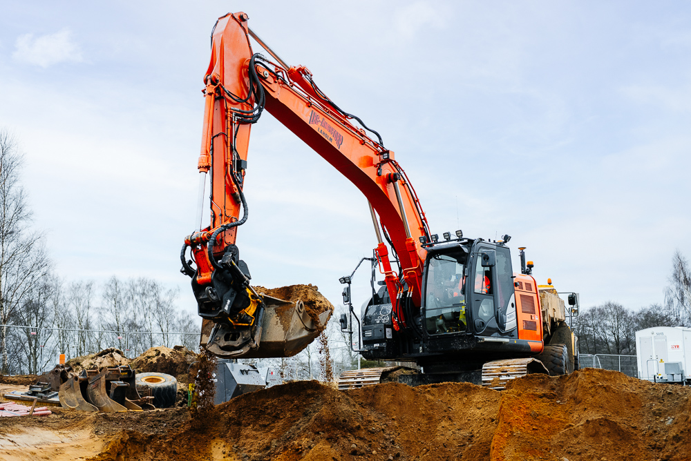 En grävmaskin med larvband utför mark & anläggnings arbete